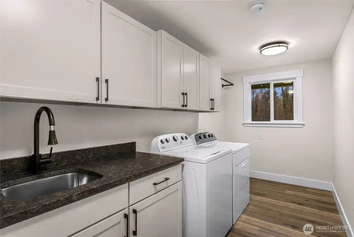 This utility room turns doing laundry into a dream! Plenty of storage space, folding space, large sink and hanging bar installed.
