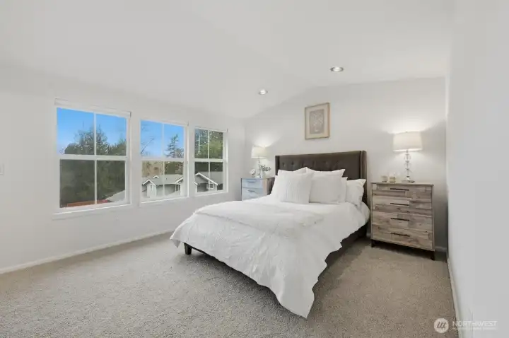 Spacious primary bedroom with vaulted ceilings on upper level