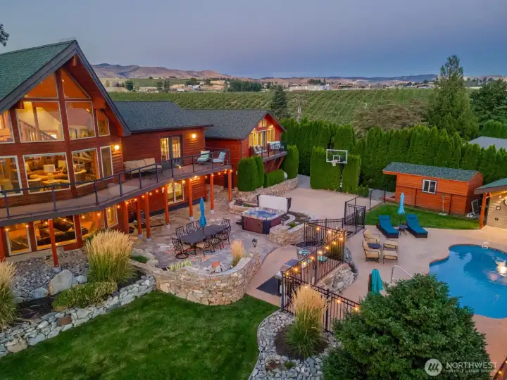 Aerial view of home and outdoor living area w/ pool, hot tub, basketball court, landscaped grounds and dining and lounge areas overlooking Lake Chelan.