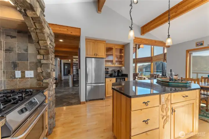 View 1 of kitchen w/ hardwood floors, stainless steel appliances, quartz countertops, wood beams, stone surround stove and oven and large windows with views of Lake Chelan.