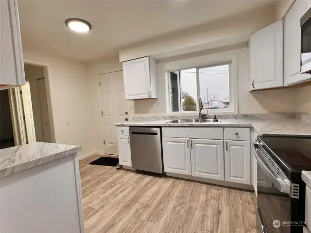 Brand new gorgeous kitchen with door to the gravel driveway area.