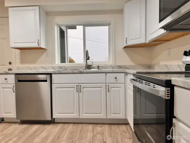 Big beautiful kitchen with lots of cabinets and window that looks out to the fenced front yard.