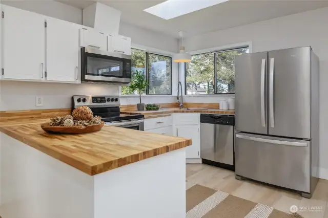 Butcher block countertop, updated hardware and lighting, and stainless appliances.