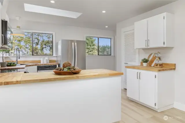 The kitchen is flooded with natural light, with large windows and a skylight.