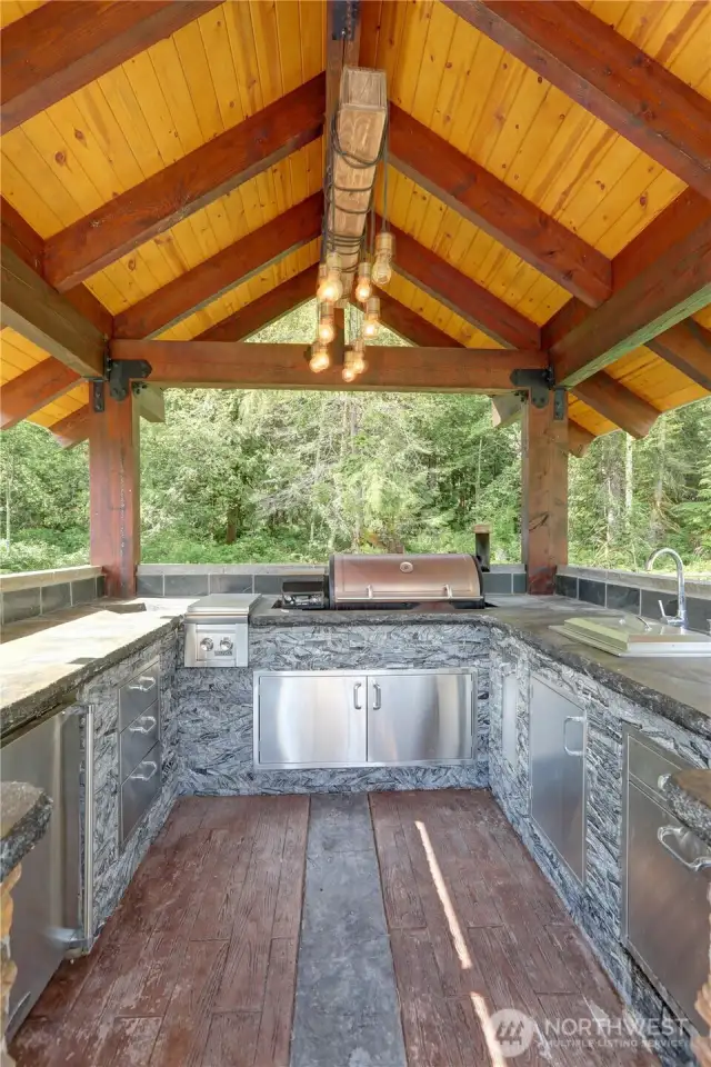 Outdoor kitchen has a built in BBQ, sink and a 2 burner stove