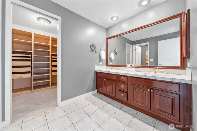 The primary bath showcases cherry wood cabinetry, dual sinks, and an oversized mirror—ideal for streamlined morning routines. A medicine cabinet offers added storage, while the ceramic tile flooring ensures easy maintenance.