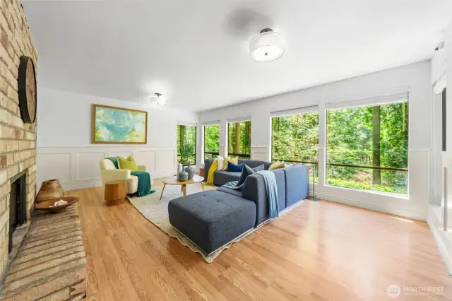 Wall-to-wall windows frame peaceful, forested views, filling the lower-level rec room with natural light and offering a luxurious, treehouse-like retreat ideal for relaxing or entertaining. Privacy blinds provide flexibility and comfort throughout the day.