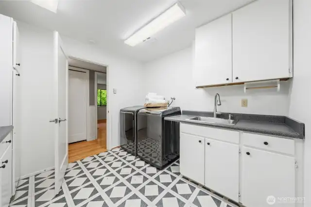 Freshly painted and well-appointed laundry room features a utility sink, generous counter space, and abundant storage on both sides—making everyday tasks feel effortless.