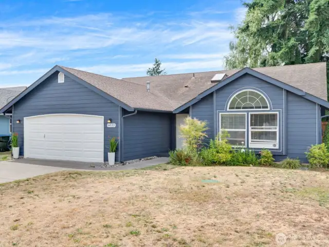 Classic front elevation with arched window and mature landscaping create a warm first impression.