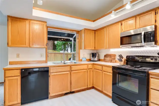 Spacious kitchen with ample cabinet storage, black & SS appliances, and large garden window overlooking the backyard.