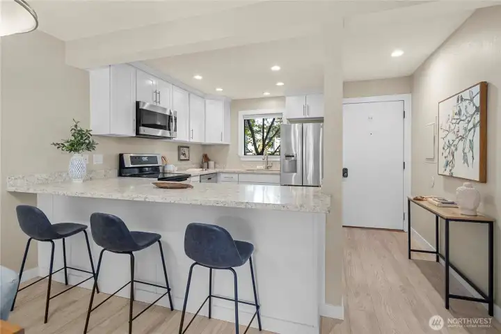 Open concept kitchen with quartz surfaces and is a perfect match to the newly installed vinyl plank flooring throughout.  All appliances transfer with property.