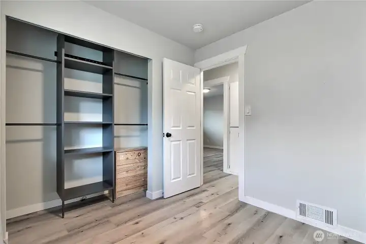 Second bedroom featuring updated flooring and a custom closet system for organized storage.