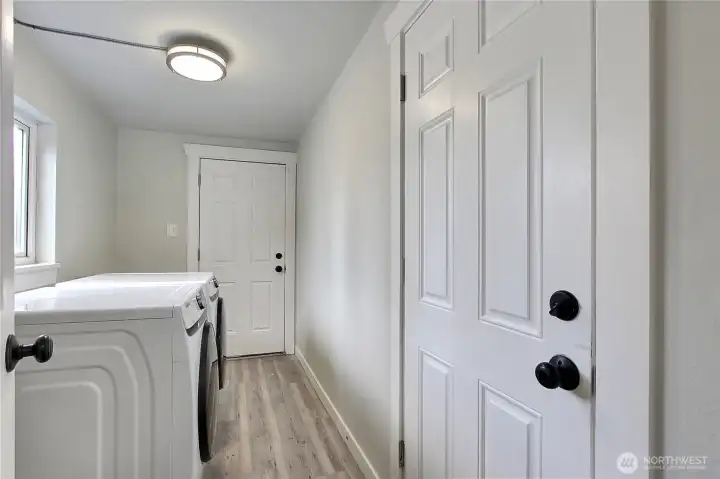 Utility room with front-load washer and dryer included and exterior door leading to the backyard.