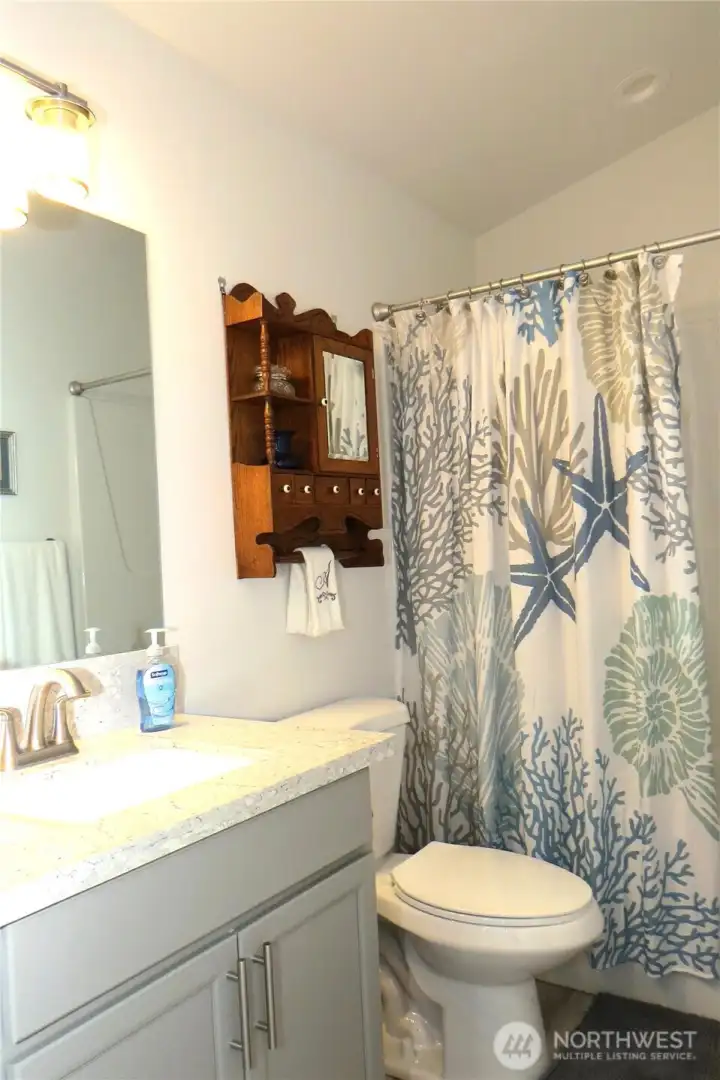 The guest bathroom also has a matching stylish vanity with quartz counter tops and shower/tub combination!