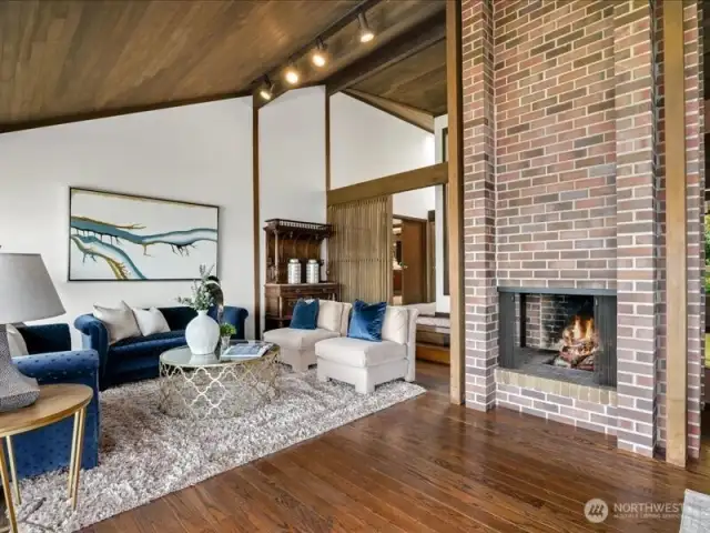 The architecturally significant three-sided brick fireplace, spanning the living and dining areas, offers warmth in cooler months while adding enduring style throughout the year.