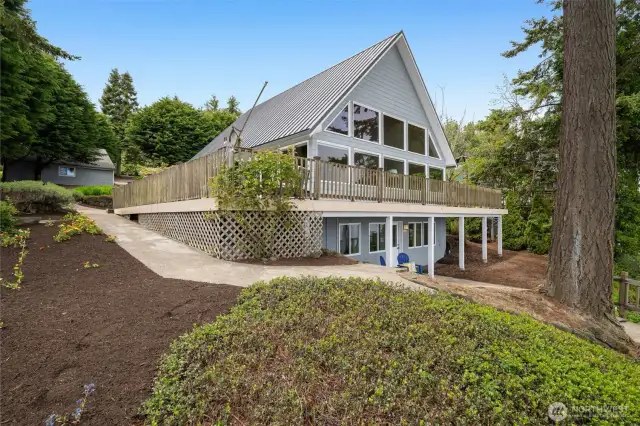 The path around the side of the home leads to the lower level as well as the lower deck and water.