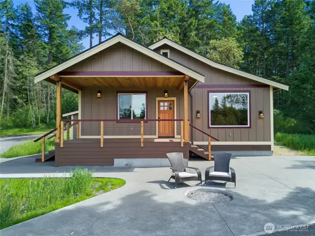 Inviting covered front porch and spacious patio with firepit, perfect for relaxing and entertaining in a private wooded setting.