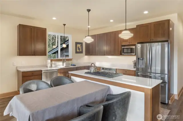 Bright, modern kitchen featuring stainless steel appliances, quartz countertops, and a spacious island with gas cooktop.