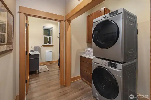 Modern laundry nook with stacked washer/dryer, custom cabinetry, and easy access to the adjoining bathroom.
