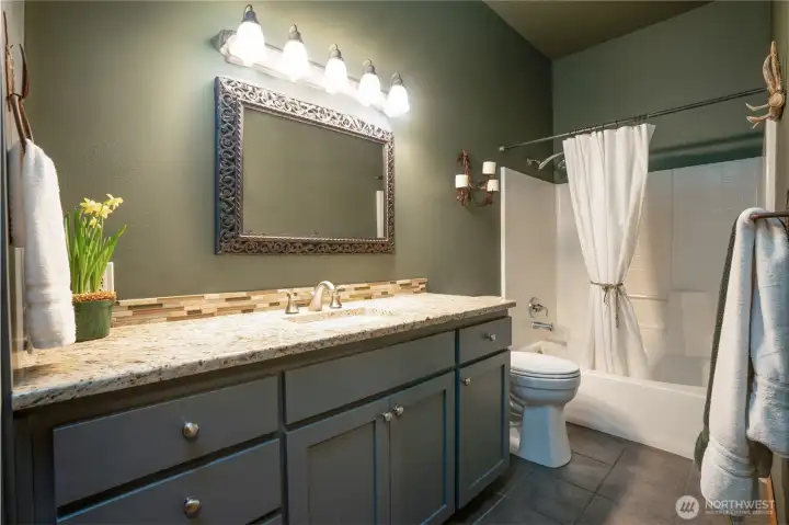 Main/full bath with granite vanity top and tile flooring.