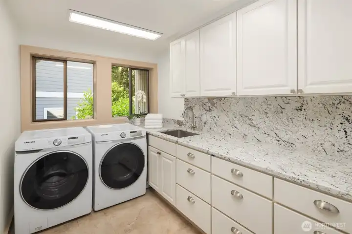 Main floor laundry room with lots of cabinetry and an abundance light!