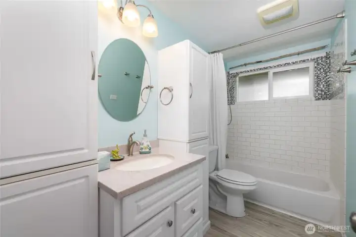 Updated bathroom with tiled shower surround and storage cupboards.