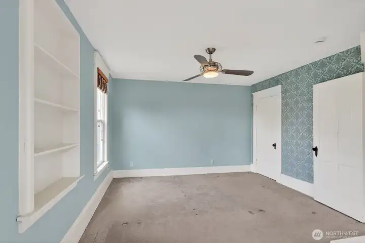 Primary bedroom with ceiling fan and original built-ins. Primary bedroom with ceiling fan and original built-ins.