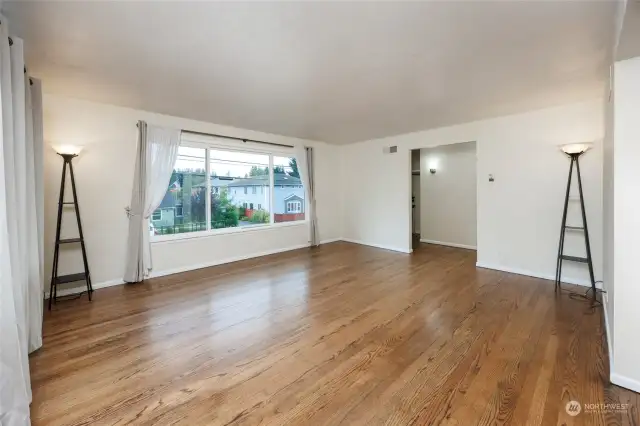 Sunny living room with picture windows and hardwood floors.