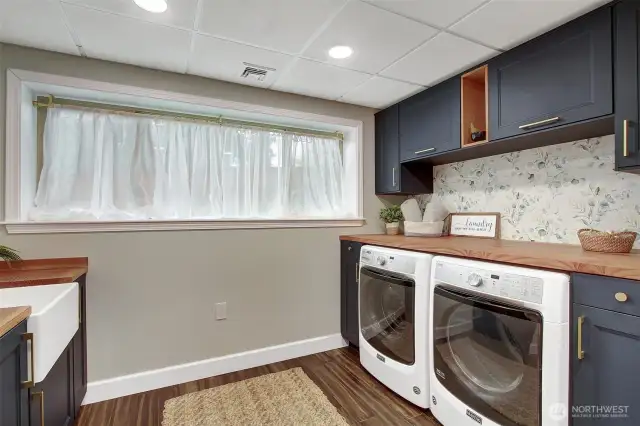 Spacious laundry room with farmhouse utility sink & storage cabinets.