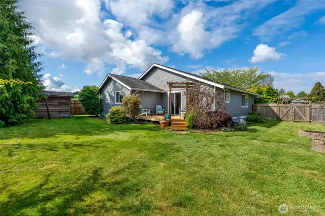 Gorgeous back yard includes an outbuilding for storage and a fire pit, far right.