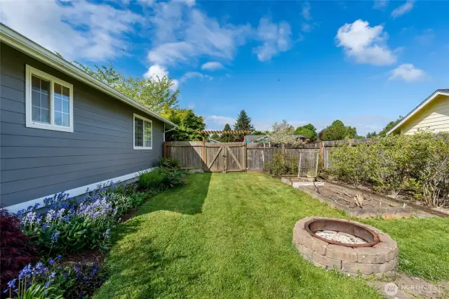 Beautiful landscaping and a head start on gardening!  Raised beds already in place with blueberry, raspberry bushes and more!  Note the double gate with access into front yard.
