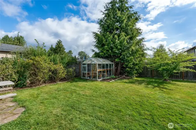 A greenhouse, berry bushes and fruit trees make for a beautiful and private back yard.