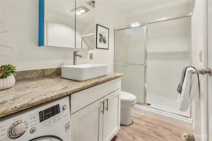 Primary bathroom with granite countertops and built in high efficiency washer/dryer.
