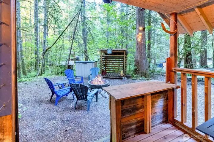 Bunkhouse covered porch view looking out to fire pit and wooded surroundings