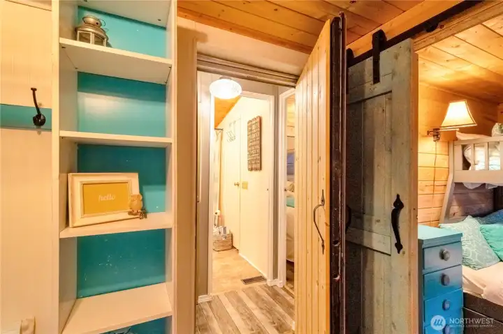 Entrance from park model into the addition with built-in shelving and sliding barn door detail
