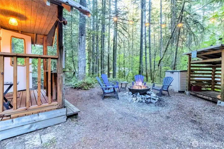 Outdoor fire pit area with seating and wooded privacy