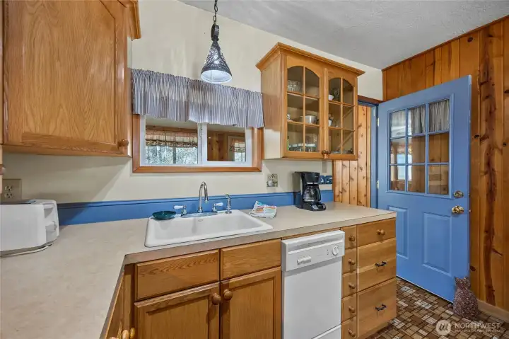 Bright kitchen workspace with double sink, glass-front cabinets, and convenient layout.