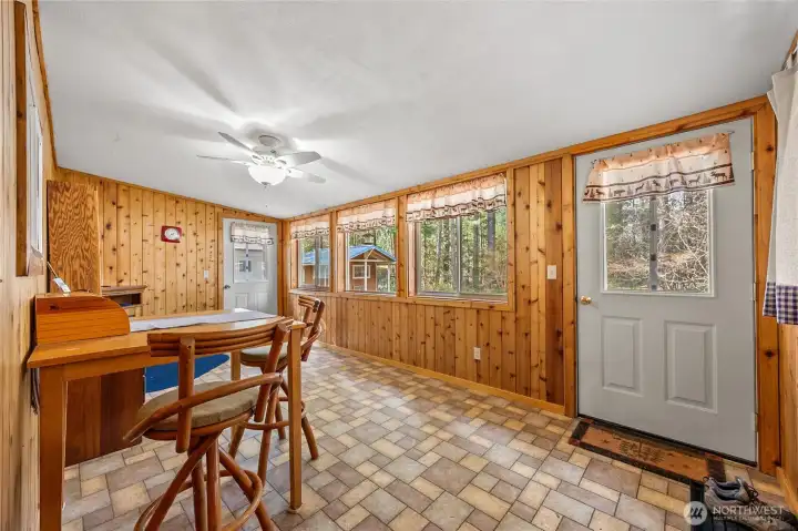 Versatile dining or bonus room with wall-to-wall windows capturing peaceful forest views and outdoor access.