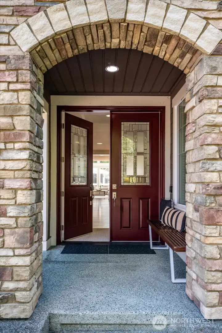 Grand covered entry framed by timeless stonework and elegant double doors creates a warm, sophisticated welcome and an unforgettable first impression.
