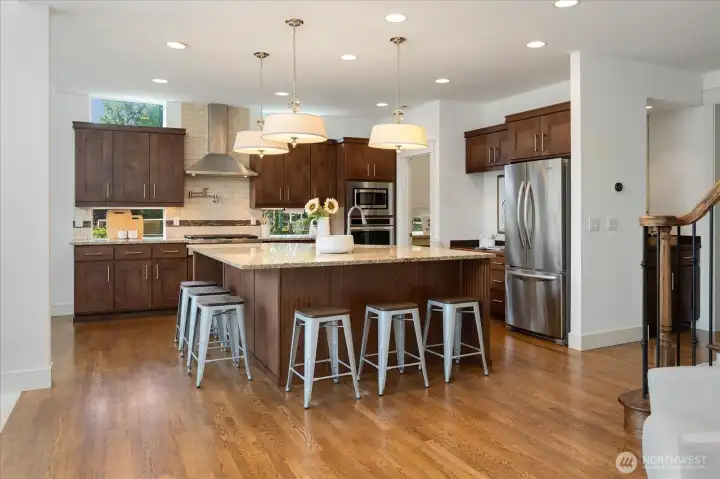 Expansive chef's kitchen is a true centerpiece, showcasing an oversized square island with seating, abundant cabinetry, generous prep space, and timeless finishes—beautifully designed for everyday living and effortless entertaining.