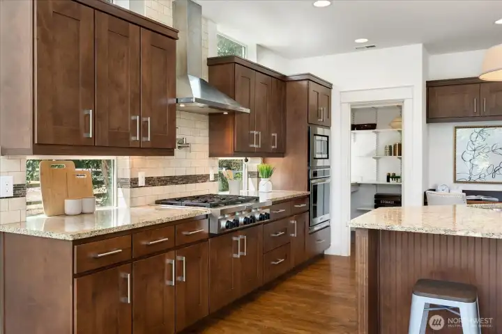 The chef's kitchen is beautifully equipped with premium stainless-steel appliances, rich custom cabinetry, generous granite countertops, and a spacious walk-in pantry—designed to make every-day cooking and entertaining effortless.