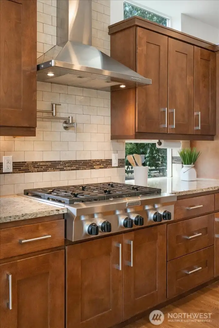 Gourmet cooking station is thoughtfully designed with a professional gas cooktop, convenient pot filler, elegant floating cabinetry, and expansive windows that fill the space with natural light—bringing together exceptional function and timeless style.