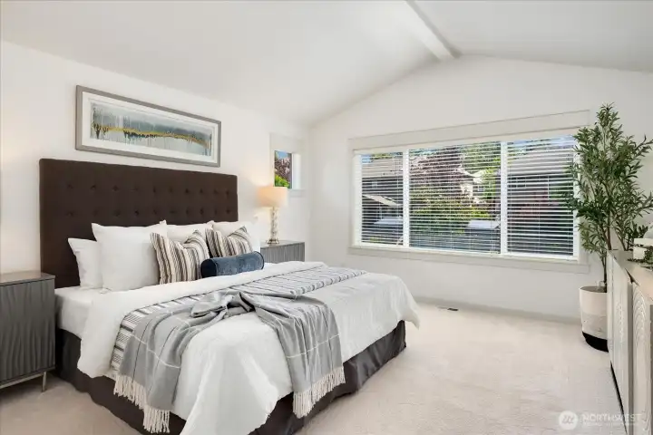 Expansive primary suite offers a bright, airy ambiance with vaulted ceilings, fresh paint, plush new carpeting, and generous windows overlooking the private backyard.