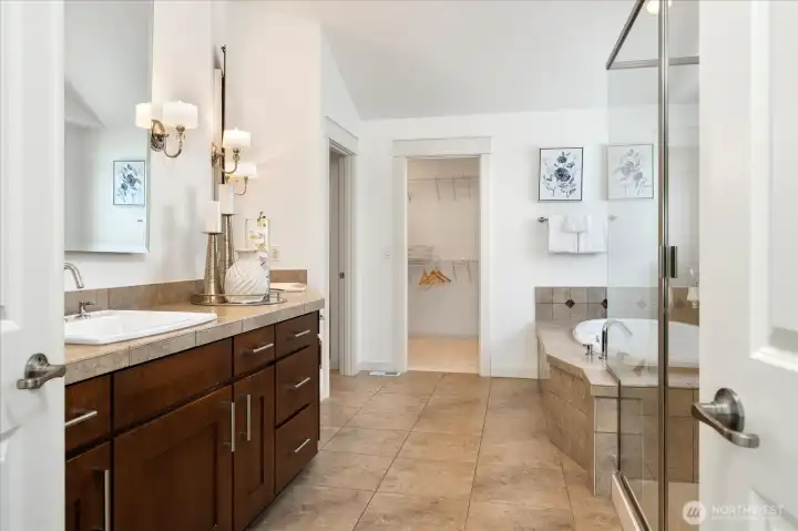 Indulge in the spa-inspired primary ensuite featuring dual vanities, a soaking tub, glass-enclosed shower, and a spacious walk-in closet designed for effortless organization.