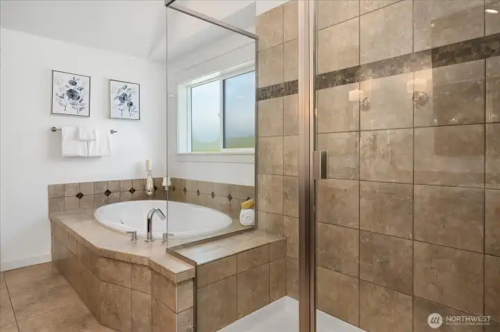 Unwind in the spa-inspired primary bath featuring a luxurious soaking tub, oversized glass shower, elegant tilework, and abundant natural light.