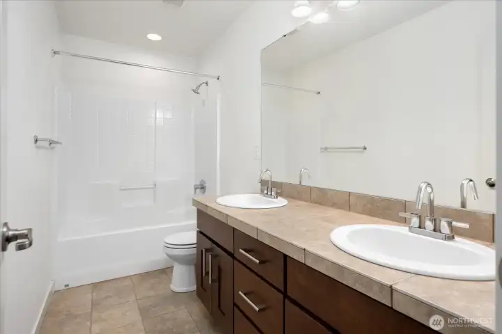 Upstairs hall bath features dual vanities, a full tub/shower combination, and generous counter space—perfectly designed to comfortably serve family and guests.