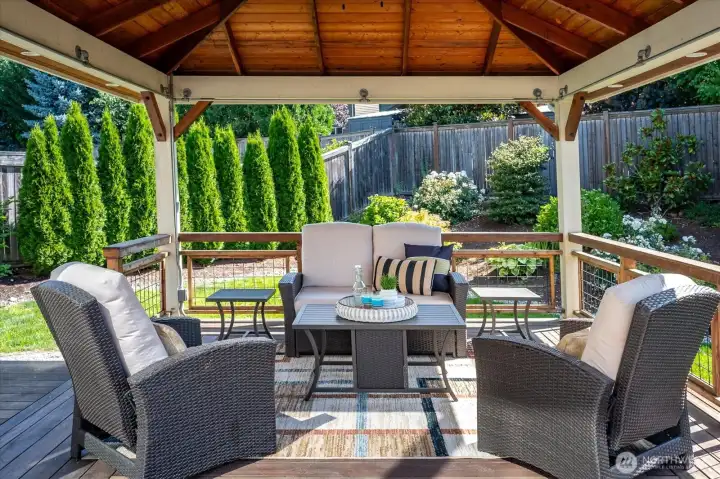 Designed for effortless entertaining, the powered gazebo offers a covered outdoor retreat with electricity, framed by colorful blooms and professionally landscaped gardens, creating a private oasis for relaxing, dining, or hosting unforgettable gatherings year-round.