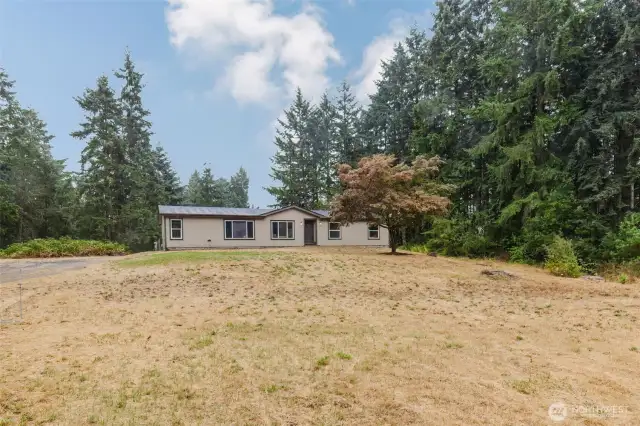 Wide front yard offering open space and privacy.