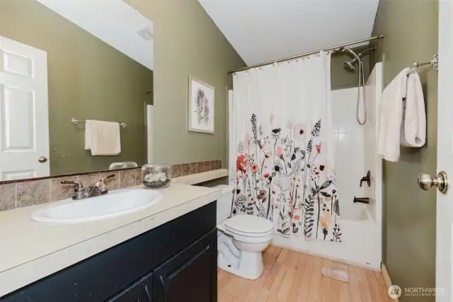 Full bathroom with double vanity and tub/shower combo.