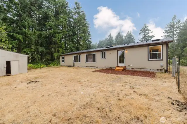 Backyard view with outbuilding and space for outdoor activities.